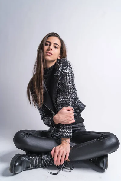 Morena sensual sentada con las piernas cruzadas en el piso del estudio Imagen De Stock
