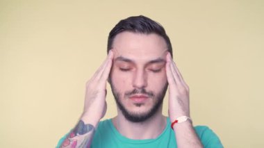 Genç sakallı adam şiddetli ağrı ya da baş ağrısından muzdarip. Parmaklarını başının kenarına yakın tut..