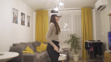 VR kulaklık ve joysticklerle oyun oynayan bir kadının yan görünümü