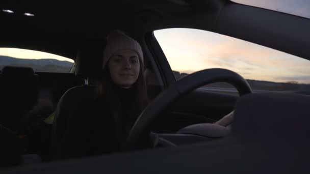 Front view of woman in winter clothes driving car and choosing song on the radio — Stock Video