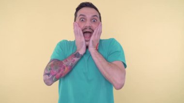 Heyecanlı, şaşırmış sakallı adam ellerini yüzüne yaklaştırıyor ve hayretle bağırıyor.