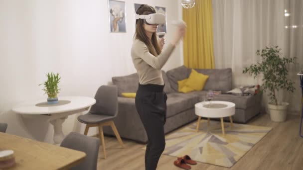 Jovem mulher vestindo vr headset enquanto joga jogos de vídeo tocando algo invisível — Vídeo de Stock