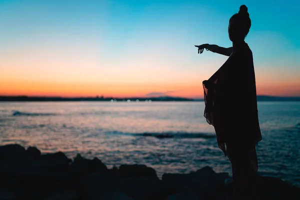 Silhouette of woman pointing forward at sunset during golden hour — Stock Photo, Image