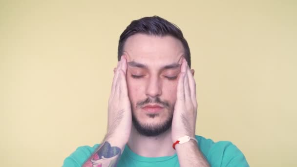 심한 두통으로 고통을 겪고 있는 젊은이, 고통을 덜기 위해 신전에 손가락을 대고 눈을 감고 있는 모습 — 비디오