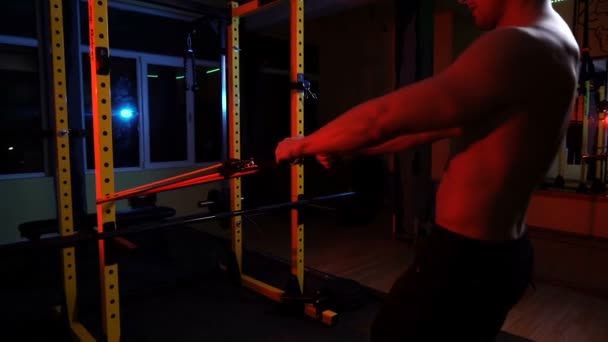 Bărbat musculos care lucrează în sala de gimnastică făcând exerciții cu benzi de rezistență pentru piept, biceps și triceps — Videoclip de stoc
