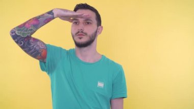 Yakışıklı adam uzaklara bakıyor, elini gözlerinin üstünde tutuyor.