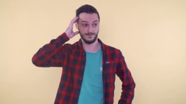 Utangaç bir adam kafasını kaşıyarak düşünüyor ve yana doğru bakıyor.