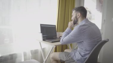 Evdeki ticaret tablolarına ve finansal verilere bakan düşünceli bir tüccar.