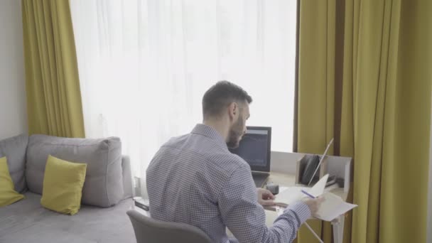 Young stock exchange trader working from home and taking notes on notepad — Stock Video