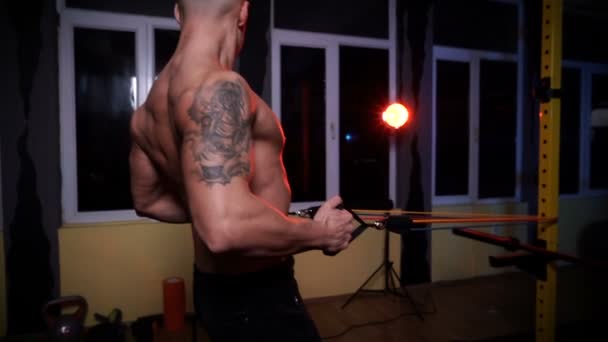 Bonito homem muscular fazendo exercícios no ginásio usando bandas de resistência — Vídeo de Stock
