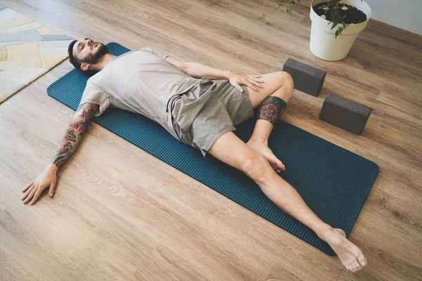 Vista superior del hombre en ropa deportiva acostado con los ojos cerrados y las piernas cruzadas relajante y respiración profunda Fotos De Stock