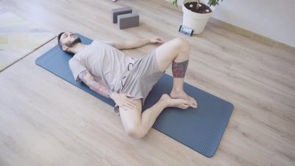 Young man relaxing with closed eyes on yoga mat after workout at home. Deep breathing — Stock Video