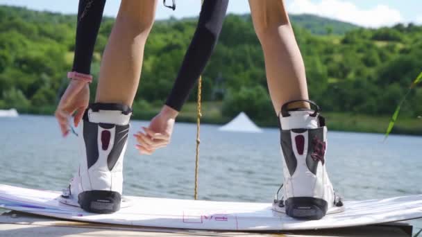 Крупним планом жінки зв'язуючі чоботи з дошкою для вейпбордингу — стокове відео