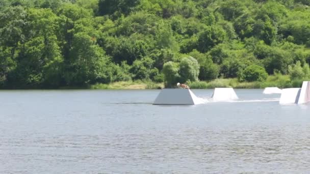 Mladý muž skákání na rampě se svým wakeboard zatímco freeriding na jezeře — Stock video