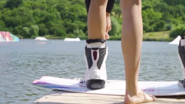 Achteraanzicht op atletische vrouwelijke benen gefixeerd in laarzen van wakeboard — Stockvideo