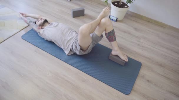 Genç sağlıklı bir adam sabah erkenden Pavanamuktasana yoga pozu veriyor. — Stok video