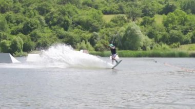 Ekstrem wakeboardcunun yavaş çekim görüntüsü numara yapıyor ve suya düşüyor
