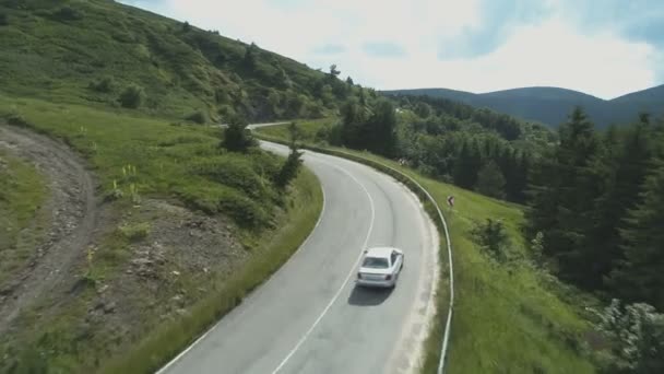 在弯曲的山路上追逐银色轿车的无人机 — 图库视频影像