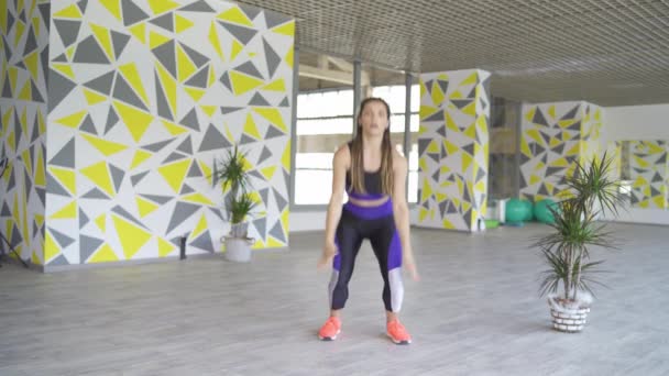 Молода підходить жінка робить стрибки присідання — стокове відео