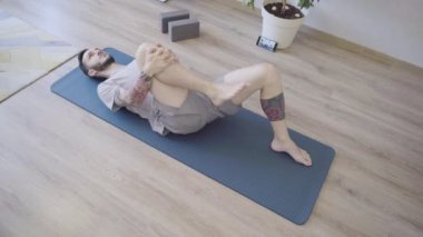 Yoga minderinde derin nefes alan genç adam. Stres atmak için evde nefes egzersizi yapan bir adam.