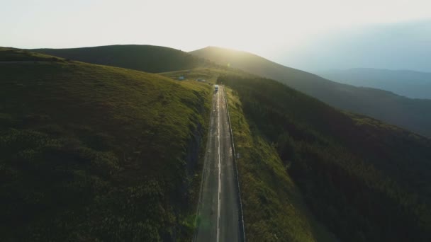 夕日の山道をゆっくり運転する白い大きな貨物車のトップビュー — ストック動画