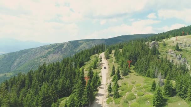 Drohne verfolgt schwarzen Geländewagen auf Feldweg in den Bergen — Stockvideo