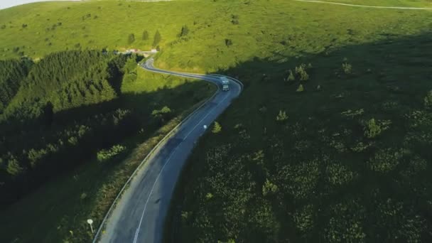 삼 림으로 뒤덮인 언덕들이 있는 시골 풍경으로 아스팔트 도로를 달리고 있는 세미 트럭 — 비디오