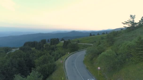 Vista aerea drone di monitoraggio SUV argento di guida attraverso la strada di passaggio in montagna con colline verdi — Video Stock