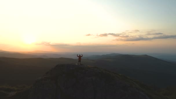 Junger Wanderer erreicht Berggipfel, streckt Arme aus für den Erfolg bei schönem Sonnenuntergang über den Bergen — Stockvideo