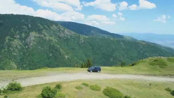 Panoramautsikt över blå fordon på kanten av en klippa med vackra skogbeklädda berg i bakgrunden — Stockvideo