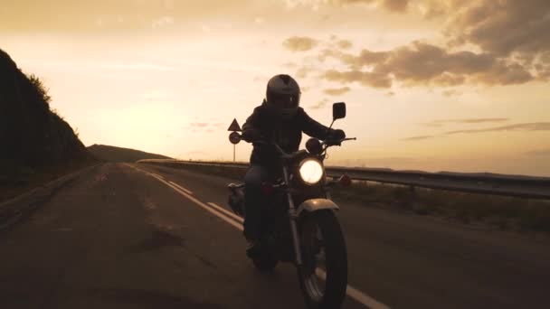 Silhouette eines Motorradfahrers auf einer Landstraße bei Sonnenuntergang — Stockvideo