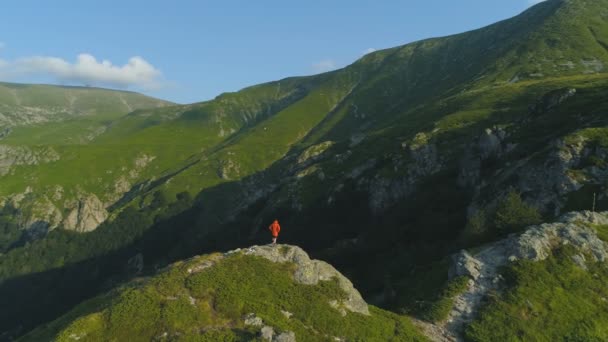 발칸 산맥의 바위 가장자리에서 오렌지 재킷 을 입고 등산을 하는 사람 — 비디오
