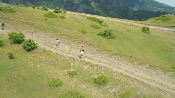 Vista aérea de los turistas caminando por un sendero en una colina verde en las montañas balcánicas — Vídeos de Stock