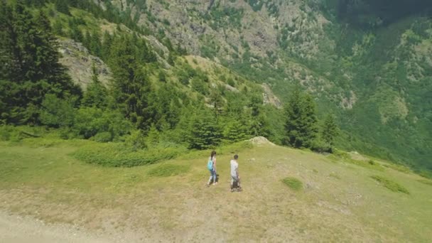 Dois caminhantes casal descansando no topo da montanha e olhando para o vale abaixo — Vídeo de Stock