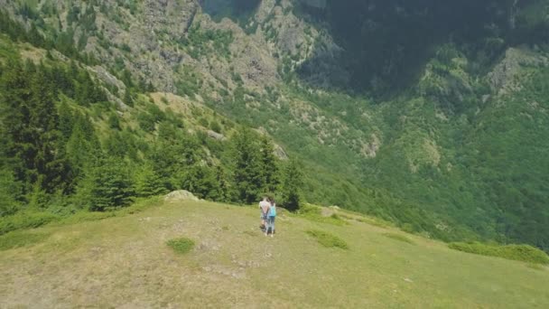 Senderistas disfrutando de la vista desde la cima de la montaña. Vista panorámica de las montañas boscosas y el valle — Vídeos de Stock