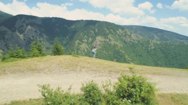 Junge Wanderin steht am Bergrand und blickt auf das tiefe Tal unten — Stockvideo