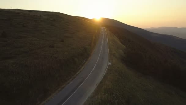 Két autó halad végig a hegyen este naplementekor. — Stock videók