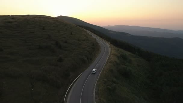 Akşamları dağ yolunda seyahat eden bir araç. Gün batımında araba sürüyor. — Stok video