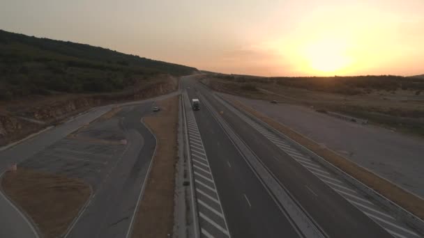 Drone segue Semi Truck em uma nova condição Rodovia sob céu pôr-do-sol dramático — Vídeo de Stock