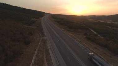 Kırsal yolda karavanı olan mavi kamyonet tarlalarla hareket halinde.