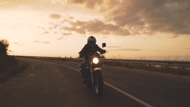 Motociclista desfruta de um passeio em sua moto ao amanhecer do sol na estrada para a liberdade — Vídeo de Stock