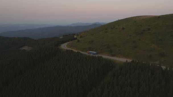 Luchtfoto van grote vrachtwagen rijden door bosrijke heuvels in de avond — Stockvideo