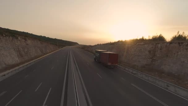 Drone jagar stor lastbil med släpvagn kör på tom motorväg vid solnedgången tid — Stockvideo