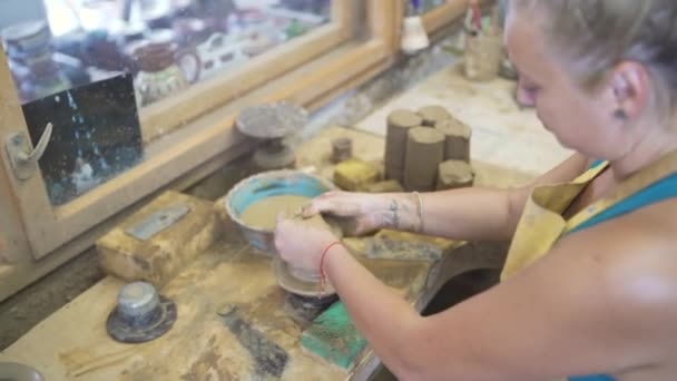 Концентрована жінка, що зосереджує кульку з глини на керамічному колесі — стокове відео