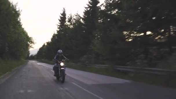 Férfi kerékpáros motorkerékpár erdei úton este felkapcsolt fényszóróval — Stock videók