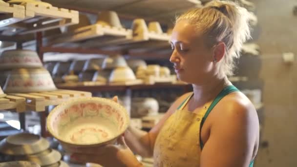 Mulher Potter artista tendo grandes tigelas de barro fora de rack de madeira na oficina de cerâmica — Vídeo de Stock