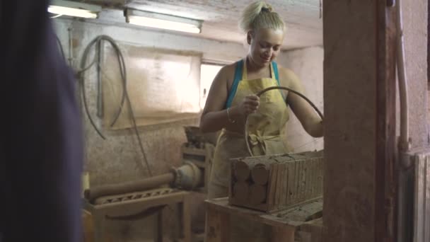 Жіночий гончар, що ріже сиру керамічну глину на шматки, використовуючи різак для арфи — стокове відео