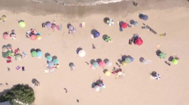 Kumsaldaki turistlerin deniz kenarında dinlenme görüntüsü.