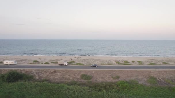 Drone Latanie w pobliżu turystycznego samochodu jadącego pustą nadmorską drogą w pobliżu piaszczystej plaży — Wideo stockowe
