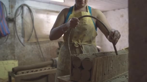 Vrouwelijke pottenbakker snijden aardewerk klei op stukken met behulp van trimmen tool — Stockvideo